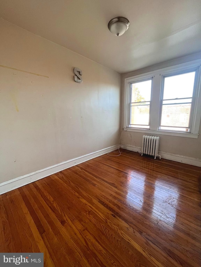 spare room with dark hardwood / wood-style floors and radiator