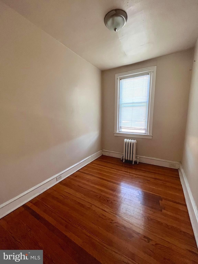 empty room featuring radiator and hardwood / wood-style floors