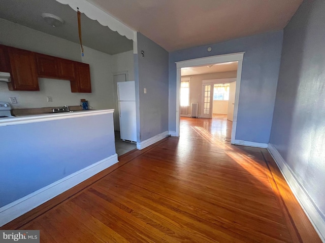 kitchen featuring light hardwood / wood-style flooring, white fridge, ventilation hood, stove, and radiator heating unit