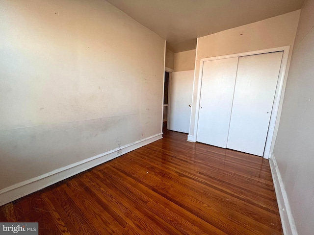 unfurnished bedroom with dark wood-type flooring and a closet