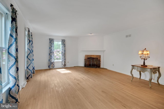 living room featuring light hardwood / wood-style floors, ornamental molding, a fireplace, and a chandelier