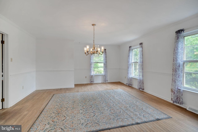 unfurnished dining area with light hardwood / wood-style floors, a notable chandelier, ornamental molding, and a healthy amount of sunlight