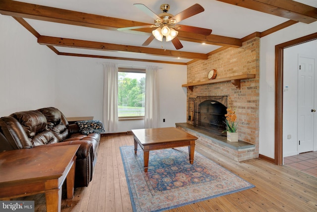 living room with a fireplace, beamed ceiling, ceiling fan, and light hardwood / wood-style floors