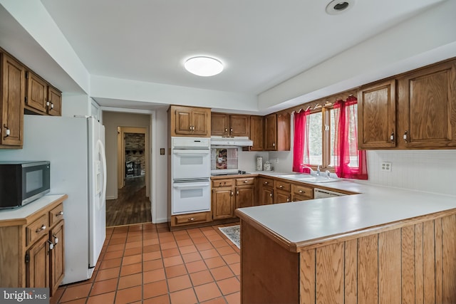 kitchen with light tile patterned flooring, black appliances, decorative backsplash, sink, and kitchen peninsula