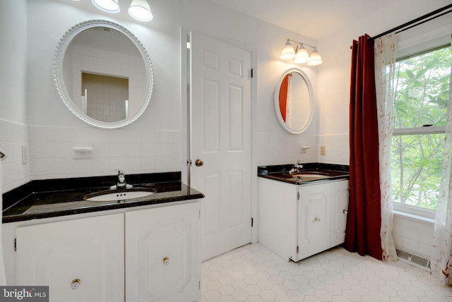 bathroom featuring vanity, a wealth of natural light, decorative backsplash, and tile patterned flooring