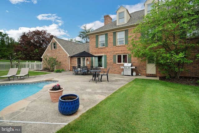 view of pool featuring area for grilling, a patio area, and a lawn