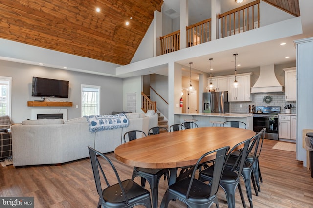 dining area with high vaulted ceiling and hardwood / wood-style flooring