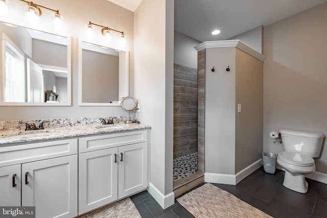 bathroom featuring double vanity, tile floors, toilet, and a tile shower