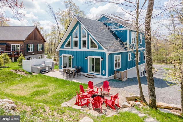 back of property featuring a patio, an outdoor fire pit, and a lawn