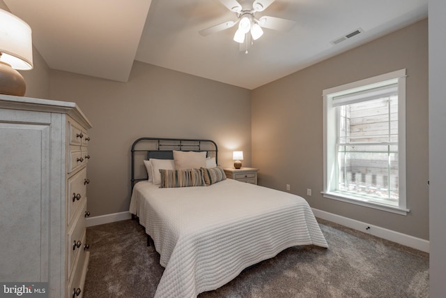 bedroom with ceiling fan, dark carpet, and multiple windows