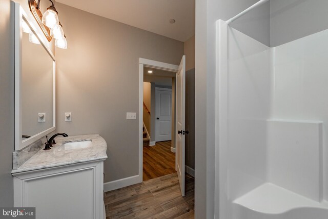 bathroom with hardwood / wood-style flooring and vanity with extensive cabinet space