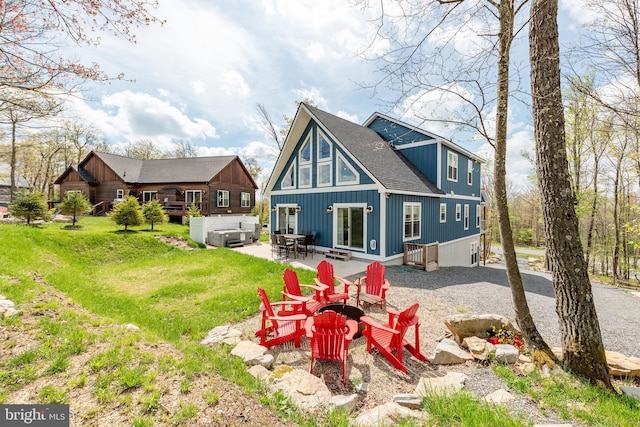 rear view of house with a patio, a yard, and a fire pit