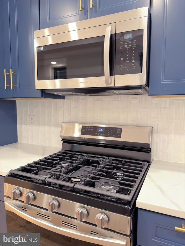 interior details with blue cabinetry, appliances with stainless steel finishes, and tasteful backsplash