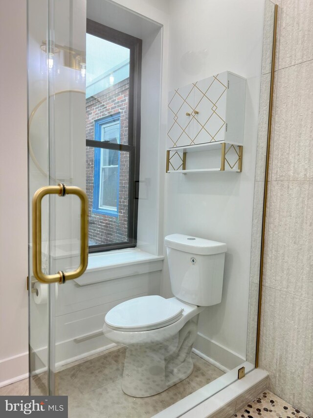 bathroom with toilet, tile patterned floors, and walk in shower