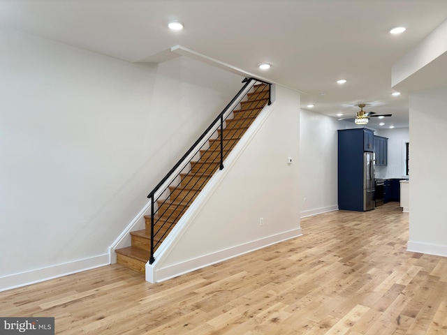 stairs featuring hardwood / wood-style flooring and ceiling fan