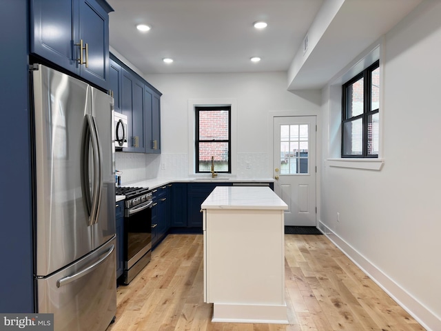 kitchen featuring sink, stainless steel appliances, tasteful backsplash, blue cabinets, and light hardwood / wood-style floors