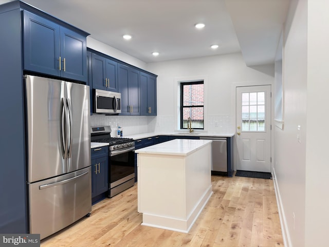 kitchen with blue cabinetry, sink, light hardwood / wood-style floors, decorative backsplash, and appliances with stainless steel finishes