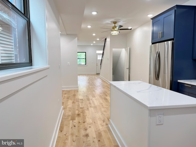 kitchen featuring blue cabinets, ceiling fan, stainless steel fridge, light hardwood / wood-style floors, and a kitchen island