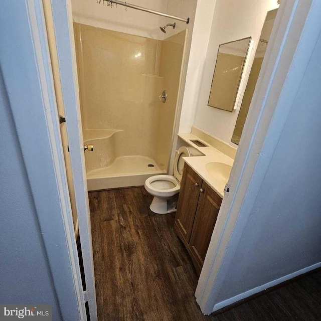 bathroom featuring vanity, wood-type flooring, toilet, and a shower