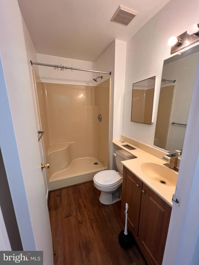 bathroom featuring a shower, vanity, hardwood / wood-style flooring, and toilet