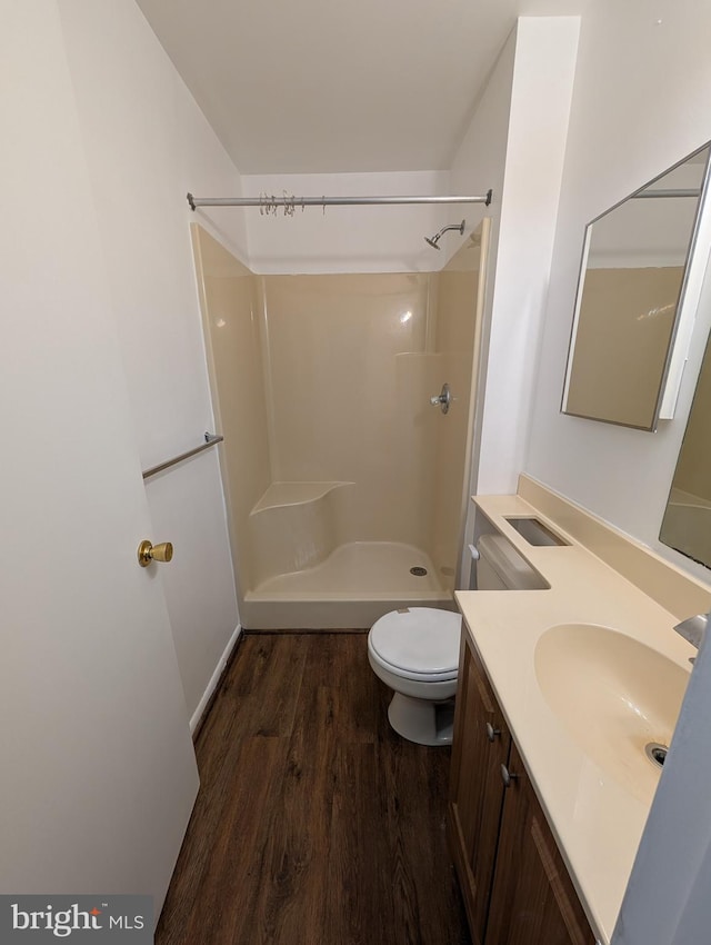 bathroom with toilet, hardwood / wood-style floors, vanity, and walk in shower