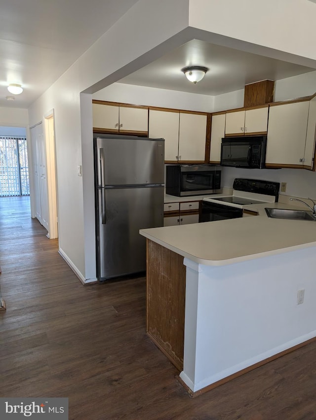 kitchen featuring appliances with stainless steel finishes, sink, dark hardwood / wood-style flooring, kitchen peninsula, and cream cabinets