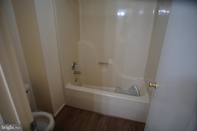 bathroom featuring bathtub / shower combination, hardwood / wood-style flooring, and toilet