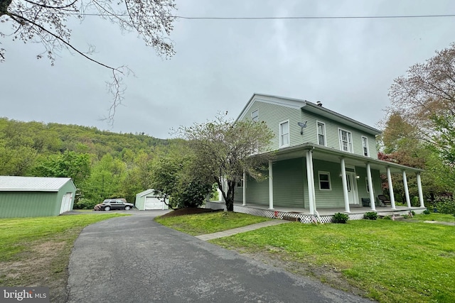 view of home's exterior with a garage, a yard, an outbuilding, and covered porch