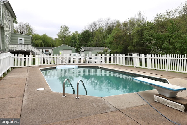 view of pool featuring a diving board, a patio, and an outdoor structure