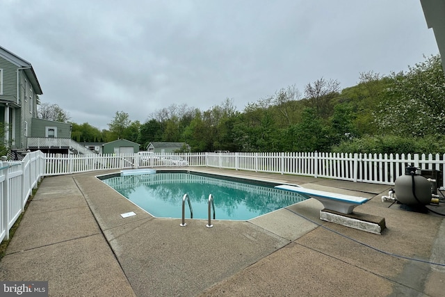 view of pool featuring a diving board and a patio