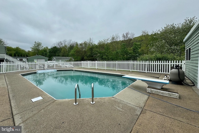 view of swimming pool featuring a diving board and a patio area