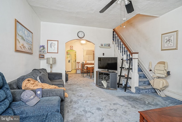 living room with carpet, ceiling fan, and a textured ceiling