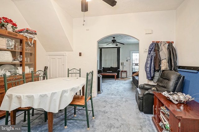 carpeted dining space with ceiling fan and vaulted ceiling