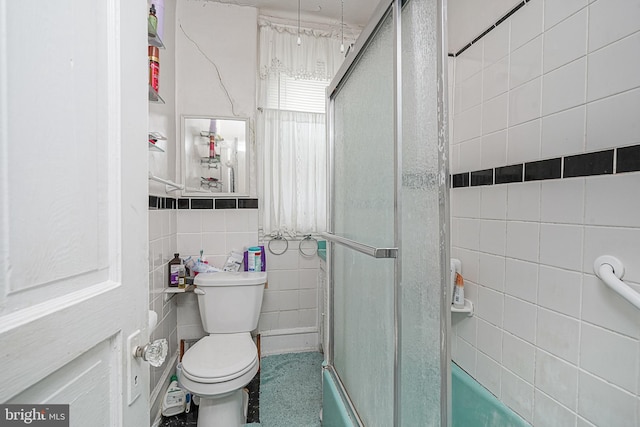 bathroom featuring tile walls and toilet