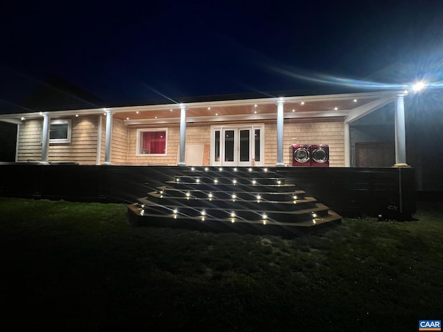 property exterior at night featuring french doors and washer and clothes dryer