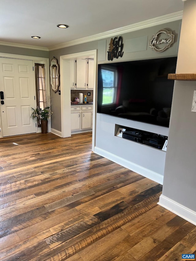 unfurnished living room with crown molding and dark wood-type flooring