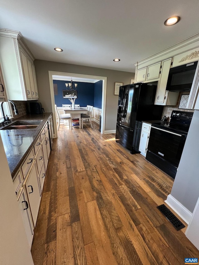 kitchen with black appliances, backsplash, hanging light fixtures, and dark hardwood / wood-style floors