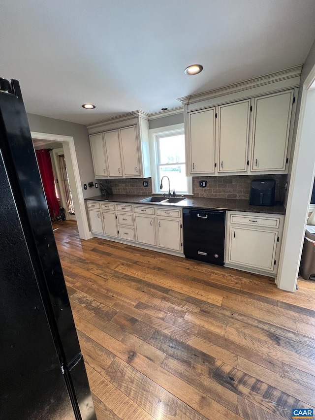 kitchen with wood-type flooring, sink, tasteful backsplash, and black dishwasher