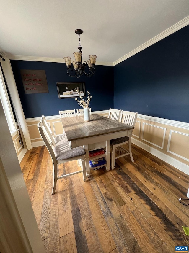 dining space with hardwood / wood-style floors, a notable chandelier, and crown molding