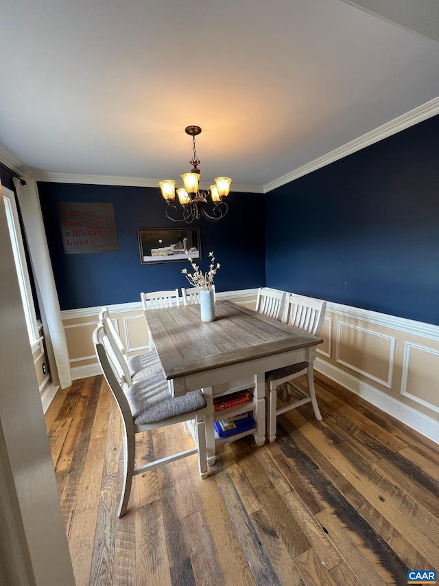 dining area with wood-type flooring, a notable chandelier, and crown molding