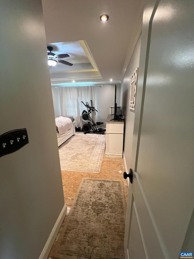 hallway featuring ornamental molding, tile flooring, and a tray ceiling