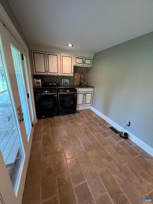 clothes washing area with washer and clothes dryer, cabinets, and sink