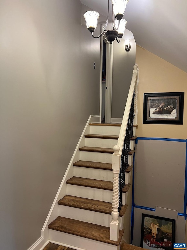 staircase with a notable chandelier