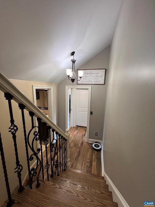 stairs with dark hardwood / wood-style flooring, a notable chandelier, and lofted ceiling