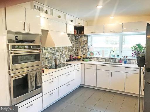 kitchen featuring black electric cooktop, backsplash, sink, dark tile floors, and double oven