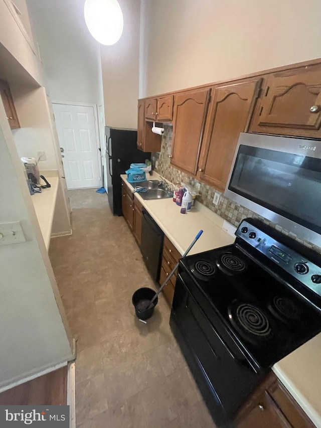 kitchen with tasteful backsplash, sink, a high ceiling, and black appliances