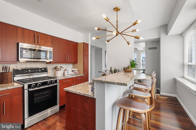 kitchen with backsplash, a healthy amount of sunlight, dark hardwood / wood-style flooring, and gas range oven