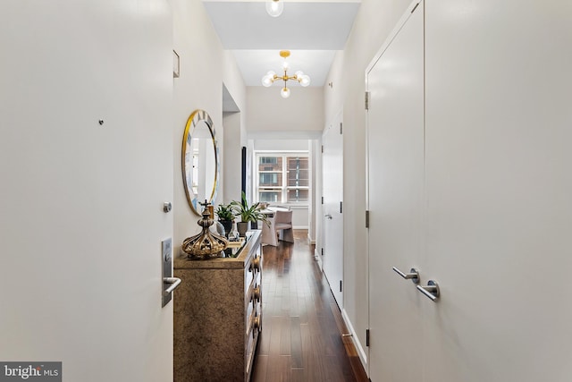 hall with dark hardwood / wood-style flooring and an inviting chandelier