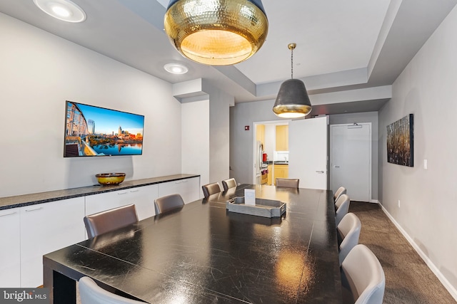 carpeted dining room with a tray ceiling