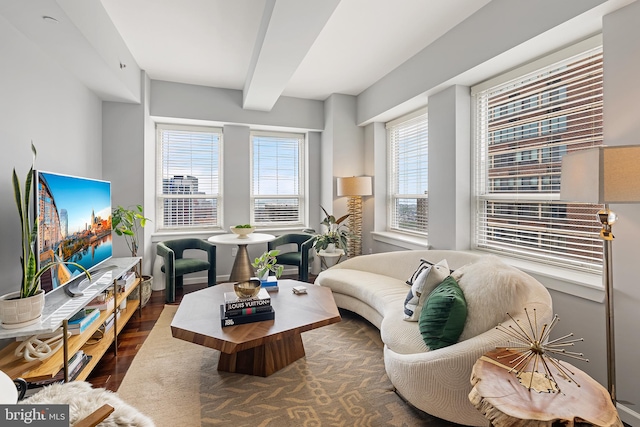 living room with a wealth of natural light, dark wood-type flooring, and beamed ceiling